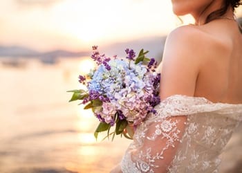 Perfectly Beautiful Take Your Wedding Season Into Consideration A bride holding a bouquet during as summertime wedding